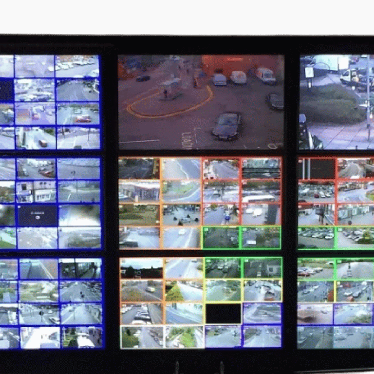 Multi-screen surveillance wall showing many live security camera feeds in a grid layout.